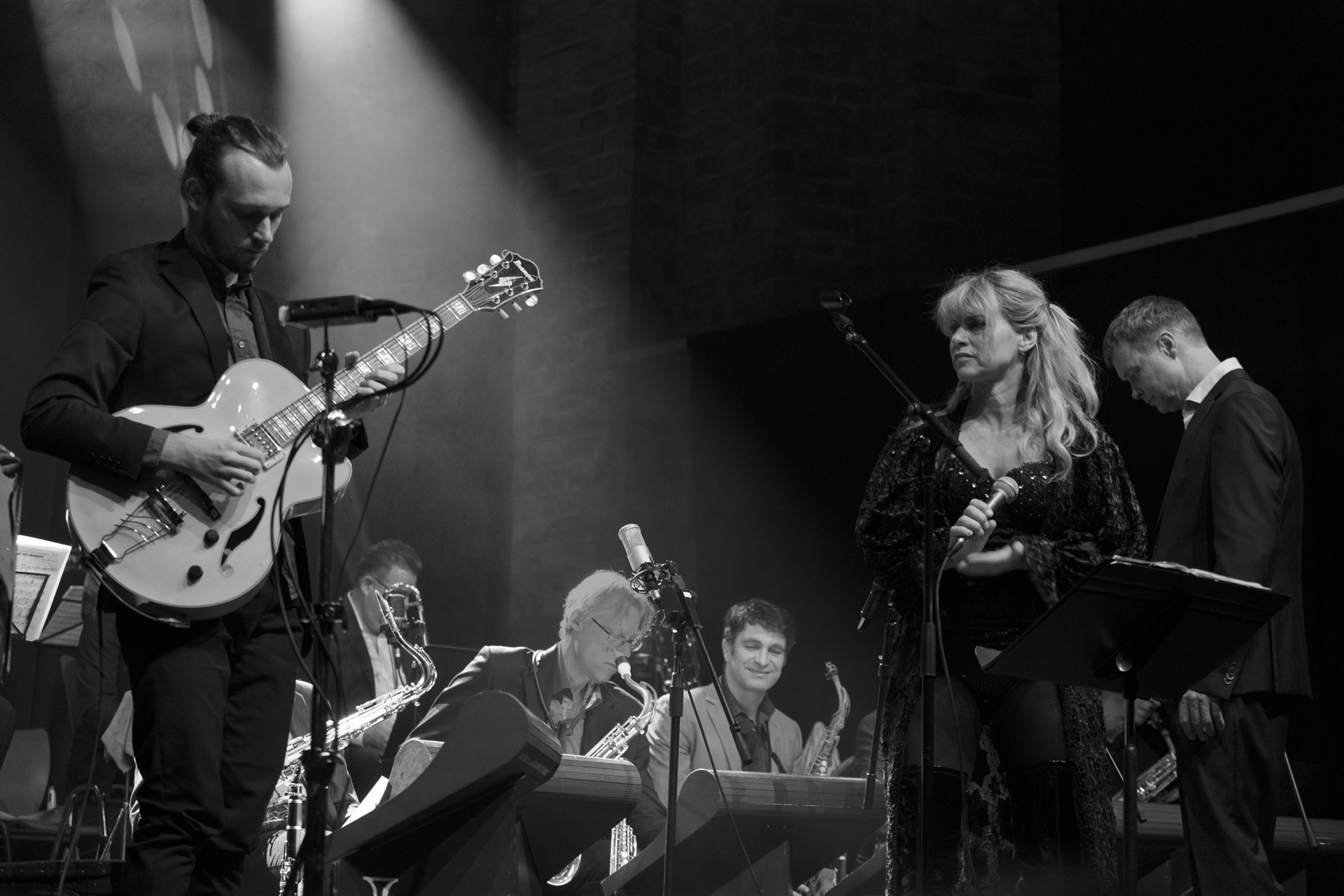 Zwart-wit concertfoto van de Molenaar Big Band met gitarist en zangeres